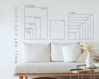 May include: A white sofa with cushions sits in front of a white wall with a black and white chart showing different sizes of wall art. The chart is labelled "Wall Art Size Guide" and shows the sizes in inches. The chart is also labelled "5" x 7" Ratio (ISO)" and "1" x 1" Ratio".
