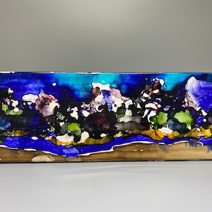 May include: Abstract painting on canvas with blue, green, gold, and white colors. The painting has a horizontal format and depicts a landscape with a sky and land.