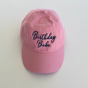 May include: A pink baseball cap with the text "Birthday Babe" embroidered in black.