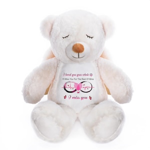 May include: A white plush teddy bear with closed eyes and a brown nose. The bear has a printed design on its chest with the text "I loved you your whole life, I'll miss you for the rest of mine, I miss you."