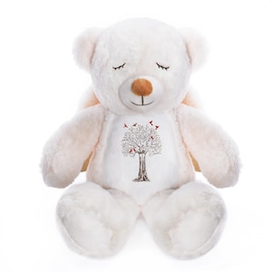 May include: A plush, cream-colored teddy bear with closed eyes and a brown nose. The bear has a tree design on its chest with red birds. The bear has small wings and is sitting upright.