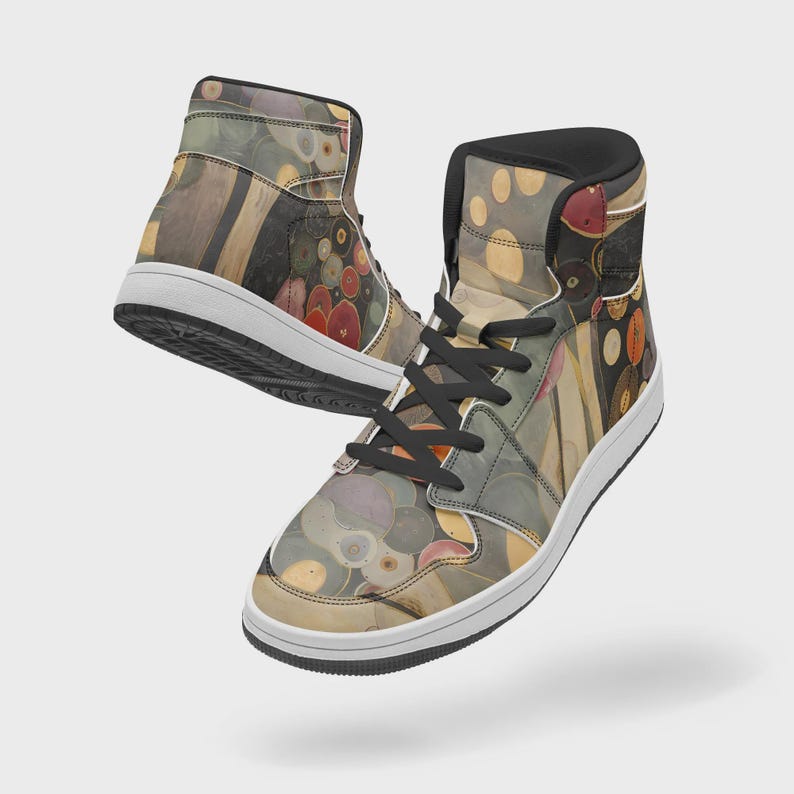 Puede incluir: Un par de zapatillas altas con un patr&oacute;n abstracto multicolor de c&iacute;rculos y formas org&aacute;nicas en tonos rojo, amarillo, gris y negro. Los zapatos tienen cordones negros, cuellos acolchados negros y suelas de goma blanca con suelas exteriores negras.