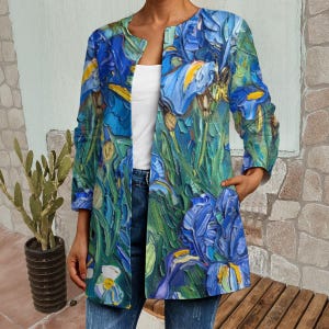May include: A long-sleeved open-front jacket featuring a vibrant blue, green, and yellow floral print reminiscent of an oil painting. The jacket has a collarless neckline, straight hem, and two side pockets, worn over a plain white top and blue jeans.