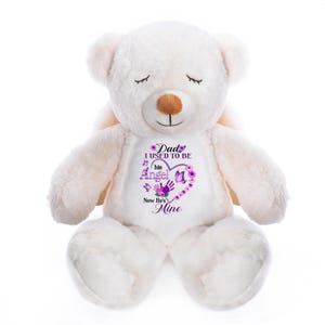 May include: A white plush teddy bear with closed eyes and small wings. The bear has a brown nose and a purple graphic on its chest that reads "Dad I used to be his Angel Now he's Mine."