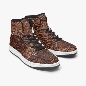 May include: A pair of high-top sneakers with a brown, textured pattern. The shoes have black laces, a white midsole, and a black collar. The overall design features a detailed, embossed appearance.