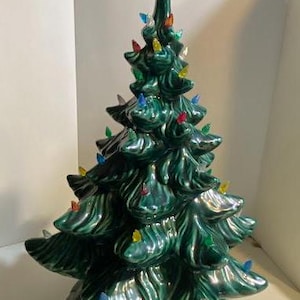 以下が含まれることがあります： 緑色の釉薬がかかったセラミック製のクリスマスツリーで、頂上に赤い星が飾られています。ツリーはカラフルなライトで飾られています。