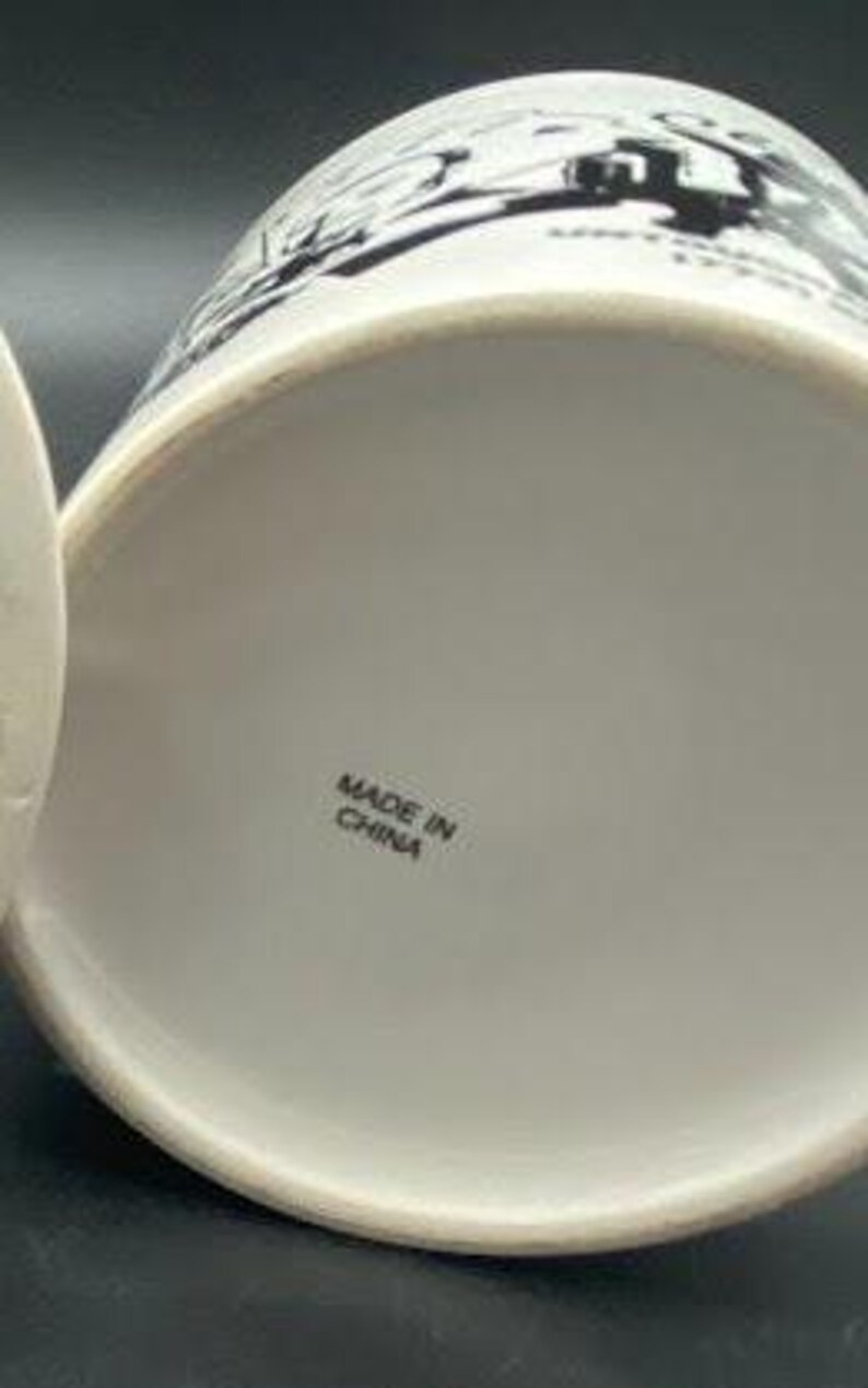 Pu&ograve; includere: Tazza in ceramica bianca con illustrazioni in bianco e nero. Il fondo della tazza riporta la scritta "Made in China."