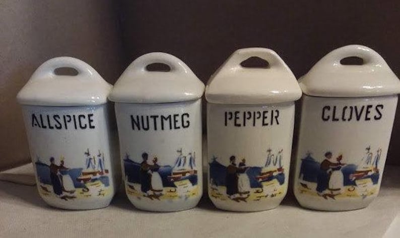 May include: Four white ceramic spice jars with blue and white painted designs. The jars are labelled "Allspice", "Nutmeg", "Pepper", and "Cloves".