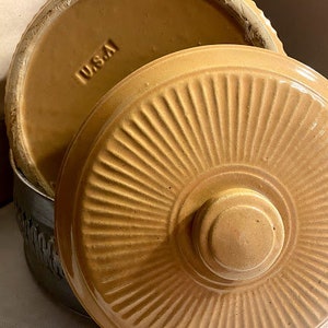 May include: A set of two brown ceramic casserole dishes with lids. The lids have a fluted design and the word "WUSTA" is visible on the top of one of the lids.