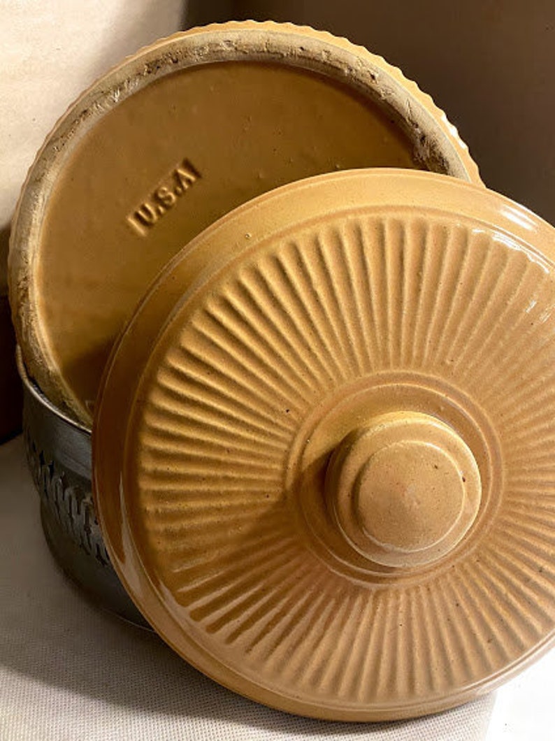 May include: A set of two brown ceramic casserole dishes with lids. The lids have a fluted design and the word "WUSTA" is visible on the top of one of the lids.