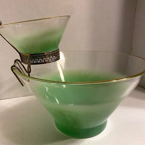 以下が含まれることがあります： 金色の縁取りと金属製のスタンドが付いた、緑色のガラス製のヴィンテージチップとディップセット。セットは、大小2つのボウルと、小さいボウルを支える金属製のスタンドで構成されています。