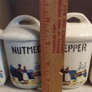 May include: Set of four white ceramic spice jars with blue and white nautical designs. The jars are labelled "Nutmeg", "Pepper", "Salt", and "Cinnamon".