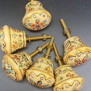 May include: Six ornate cabinet knobs with a cream base and gold accents. Each knob features a different floral design with colourful details.
