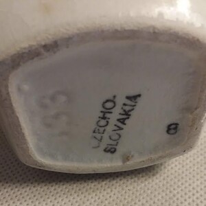 May include: Close-up of the base of a white ceramic vase with the text "UZECHO. SLOVAKIA" and the number "139" printed on it.
