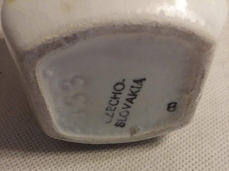 May include: Close-up of the base of a white ceramic vase with the text "UZECHO. SLOVAKIA" and the number "139" printed on it.