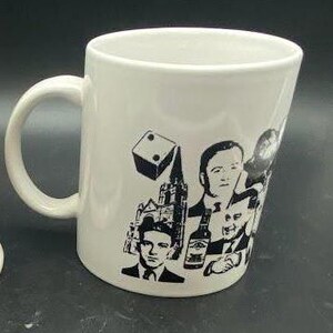 Pu&ograve; includere: Tazza da caff&egrave; in ceramica bianca con un design in bianco e nero che presenta un dado, una chiesa e diversi volti di uomini.