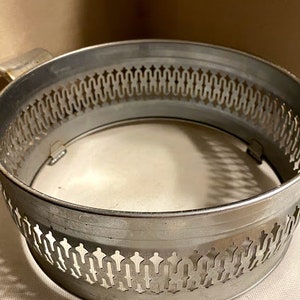 May include: Silver metal serving tray with a decorative, openwork design around the rim. The tray is circular and has a smooth, reflective surface.