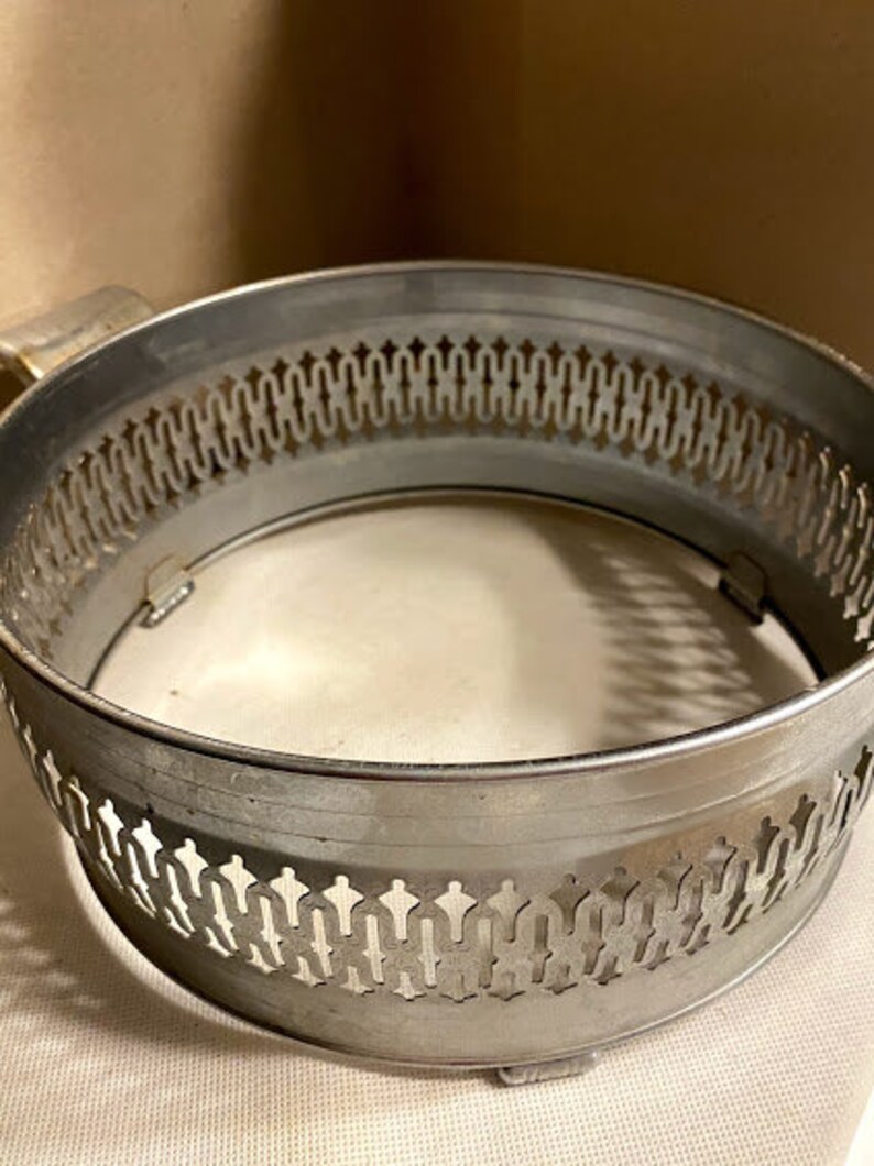 May include: Silver metal serving tray with a decorative, openwork design around the rim. The tray is circular and has a smooth, reflective surface.