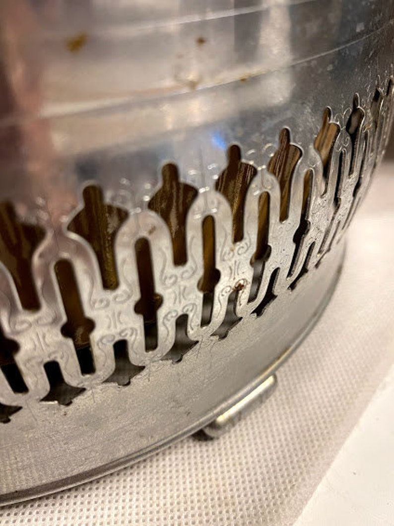 May include: Silver metal bowl with a decorative, ornate design. The bowl has a scalloped edge and a raised, intricate pattern.