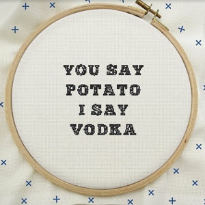 Op de afbeelding: Een witte borduurring met de tekst "You say potato I say vodka" in zwarte letters.