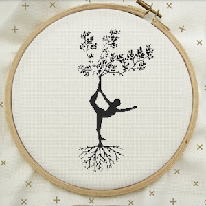 May include: Black and white cross-stitch embroidery design of a person doing yoga in a tree pose with roots growing from their feet.