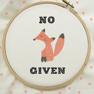 May include: A white embroidery hoop with a cross-stitch design of a red fox with the text "NO GIVEN" in black.