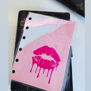 May include: A pink and white planner insert with a pink dripping kiss graphic. The text "Shop Butterflykisses" is visible in the top right corner.