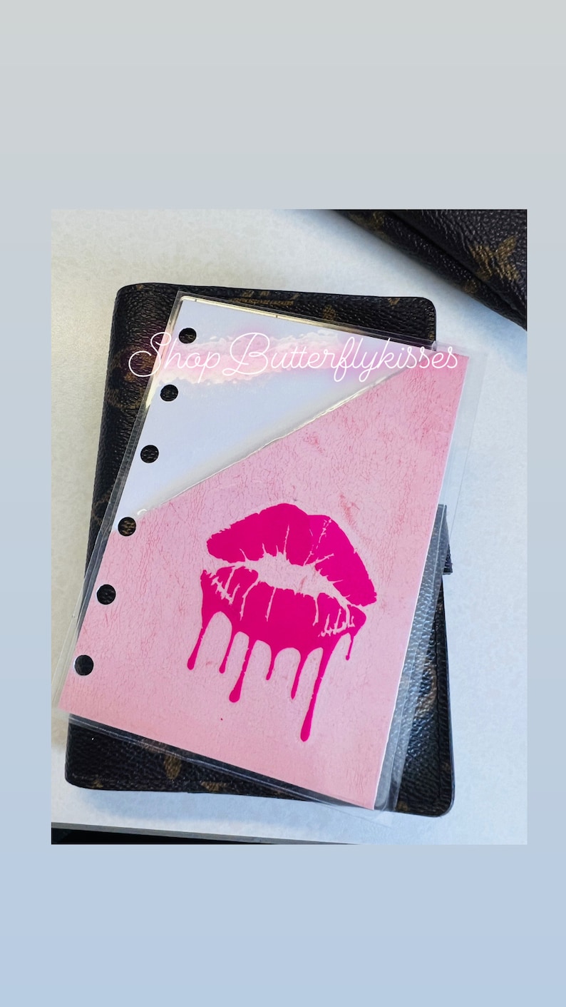 May include: A pink and white planner insert with a pink dripping kiss graphic. The text "Shop Butterflykisses" is visible in the top right corner.
