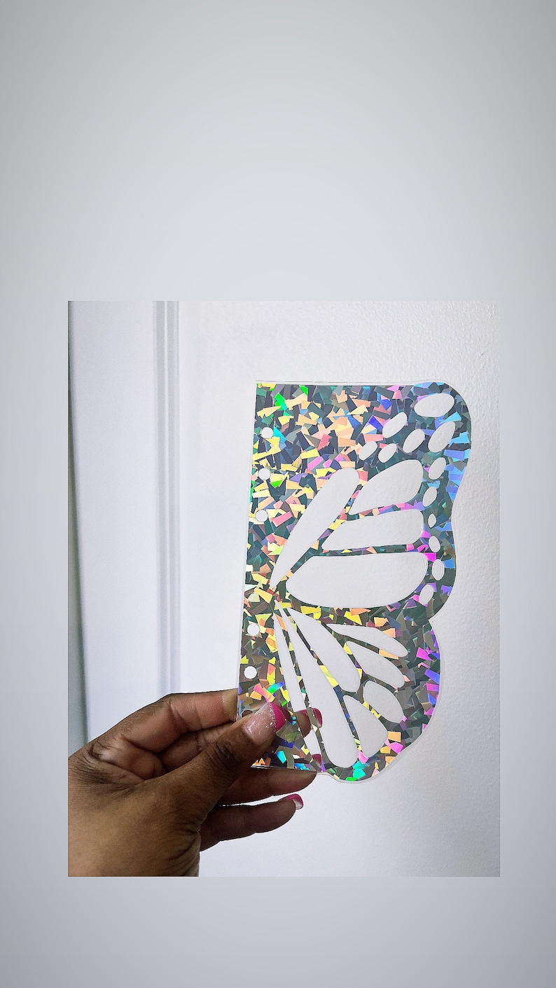 May include: A holographic butterfly wing stencil with a white butterfly design. The stencil is made of a clear, iridescent material.