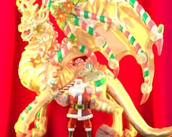 May include: A gold and white dragon figurine with candy cane and swirl decorations. The dragon is standing on a base with a Santa Claus figurine in front of it.