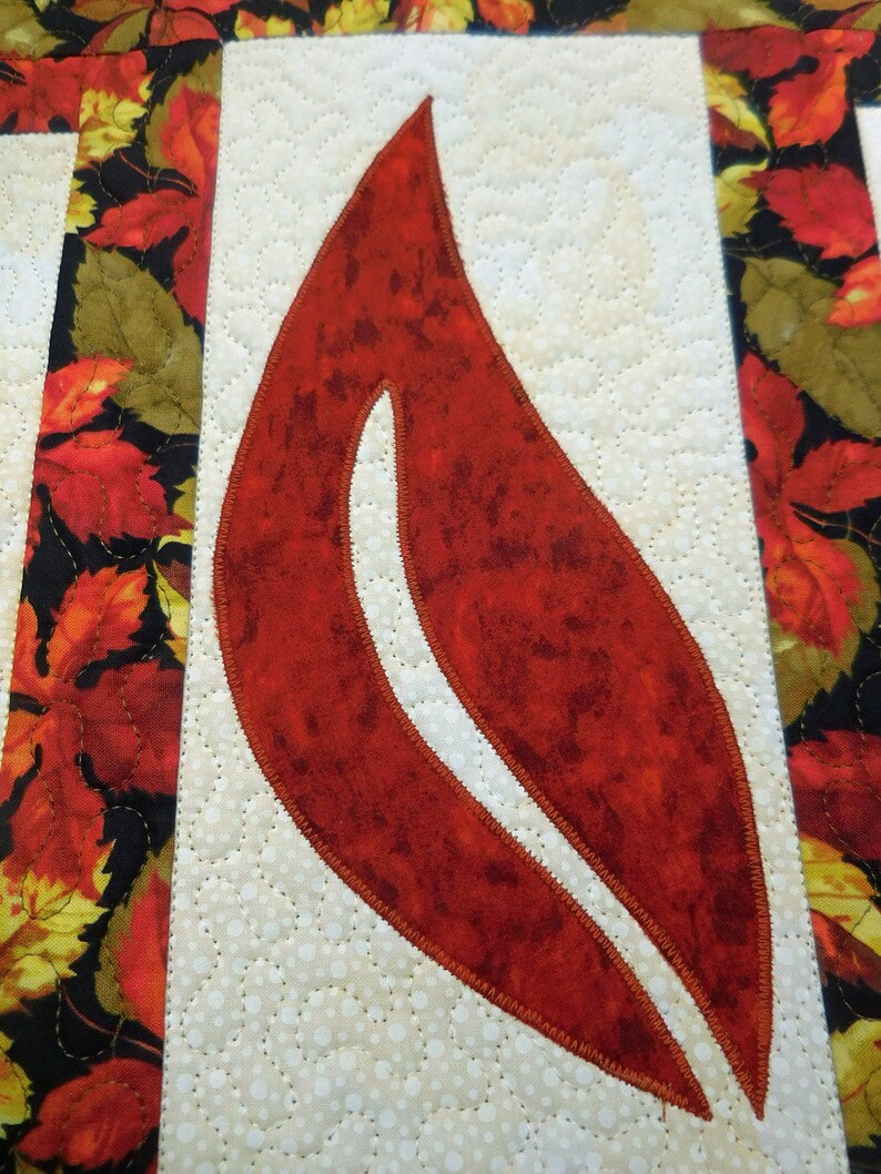 以下が含まれることがあります： 白い背景に赤い布の葉。葉は茶色の糸で縫われており、まだら模様の質感がある。