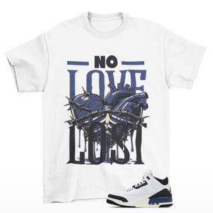 May include: White t-shirt with a graphic of a heart with barbed wire and dripping blood. The text "NO LOVE LOST" is printed on the shirt. A pair of white and blue sneakers are also pictured.