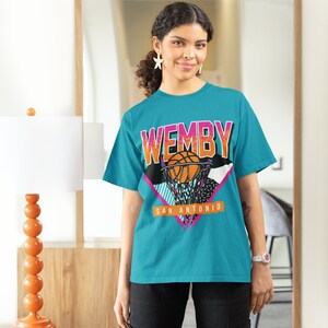 May include: A turquoise t-shirt with a graphic print of a basketball player dunking a basketball. The graphic includes the text "WEMBY" and "SAN ANTONIO".