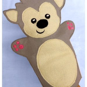 May include: Gray felt hand puppet with a beige face, black nose, and pink paw prints. The puppet has a stitched smile and is designed to fit on a hand.
