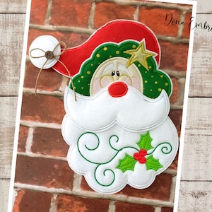 May include: A white felt Santa Claus head peeking out of a brick chimney. The Santa has a red hat, green beard, and a holly sprig with red berries.