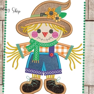 Peut inclure: Motif de scarecrow brodé avec un chapeau de paille, une écharpe et un short en jean. L'épouvantail a un visage souriant avec des joues roses et un nez rouge. Le motif comprend le texte "Dona Embroidery Shop".