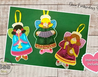 Puede incluir: Tres adornos de ángeles bordados con diferentes instrumentos musicales. Los ángeles llevan vestidos coloridos y tienen halos. El texto "Instructions Included" está en un corazón rosa.