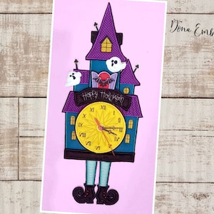 May include: A purple and blue Halloween clock with a clock face, a bat, and ghosts. The clock is shaped like a haunted house and has legs and shoes. The text "Happy Halloween!" is on the clock.