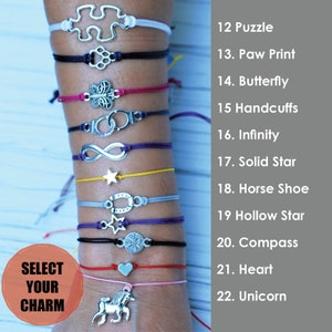 May include: A selection of charm bracelets with various silver-toned pendants, including a puzzle piece, paw print, butterfly, and infinity symbol. Each bracelet features a different colored cord, with the text "SELECT YOUR CHARM" in a circular graphic.