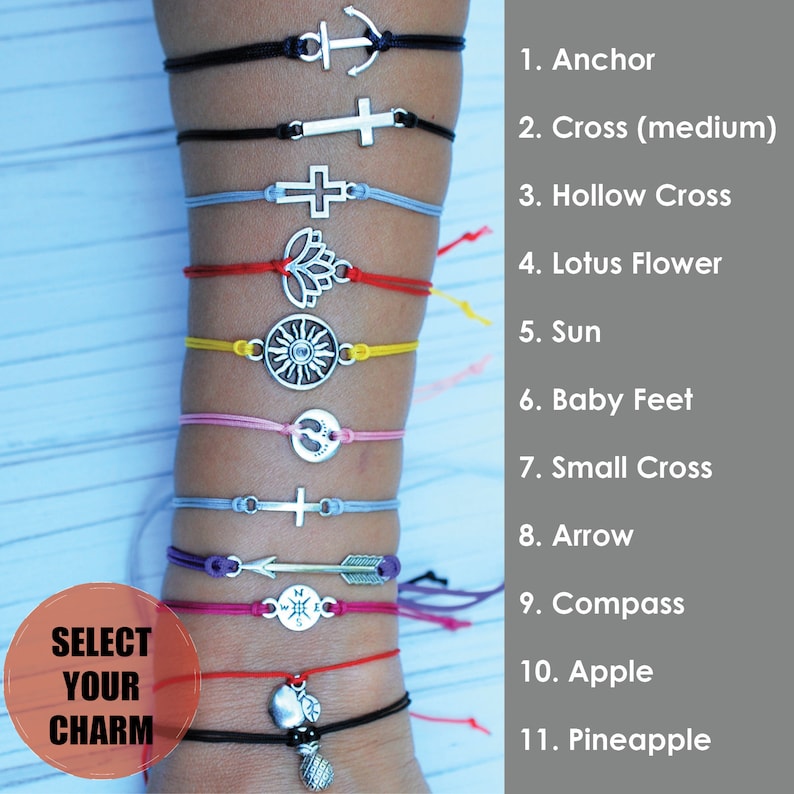 May include: A selection of charm bracelets with various silver-toned pendants, including an anchor, cross, lotus flower, sun, and arrow. The bracelets feature adjustable cords in black, red, yellow, pink, and blue. The text "SELECT YOUR CHARM" is visible.
