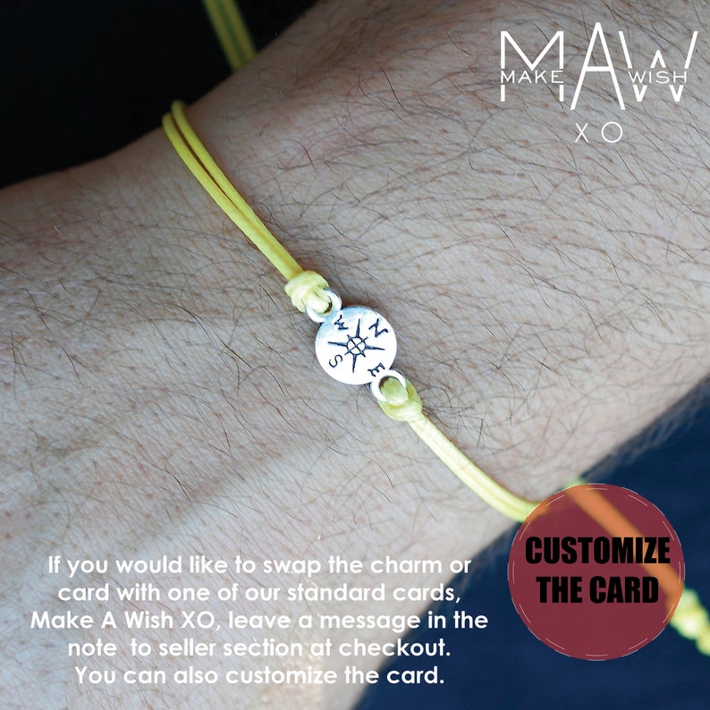 May include: A yellow cord bracelet with a silver compass charm. The bracelet is tied with knots and is shown on a wrist. The compass charm has the letters N, E, S, and W. The text "MAW MAKE WISH XO" is in the background.