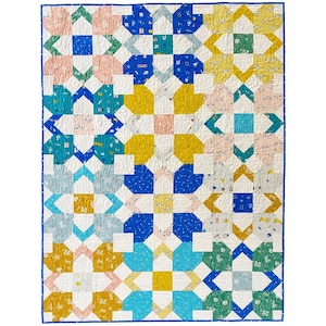 Puede incluir: Un edredón de patchwork colorido con un patrón geométrico repetitivo. El edredón presenta cuadrados y diseños de estrellas en tonos de azul, amarillo, rosa y verde, sobre un fondo blanco. El edredón está bordeado con un borde azul.