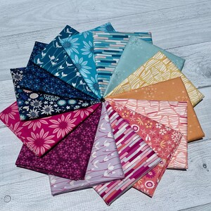 Puede incluir: Una colección de 12 cuadrados de tela en una variedad de colores y patrones, incluyendo diseños florales, geométricos y abstractos. Las telas están dispuestas en un círculo, con los colores que pasan del azul al rosa.