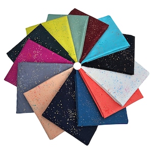 以下が含まれることがあります： 黒、白、赤、青、緑、ピンク、黄など、さまざまな色で斑点模様が施された14枚の布の正方形の集まり。布の正方形は円形に配置され、各正方形の端が重なっています。