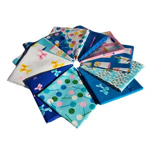May include: A collection of 10 fabric squares featuring various patterns in shades of blue, pink, and yellow. The patterns include balloons, lollipops, and geometric designs.
