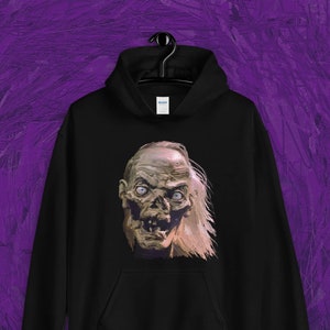 Puede incluir: Sudadera con capucha negra con un estampado gráfico de una cara humana pálida, en descomposición, con cabello largo y blanco.