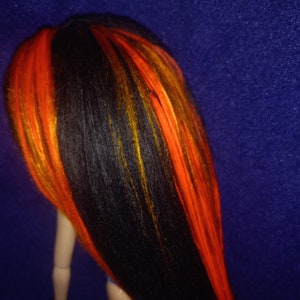 May include: A doll with long black hair with streaks of orange and yellow.