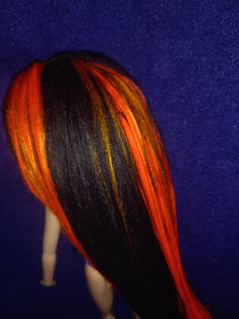 May include: A doll with long black hair with streaks of orange and yellow.