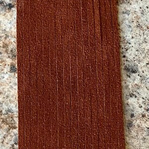May include: A brown leather fringe trim with a length of approximately 6 inches. The fringe is made of thin strips of leather that are sewn together.