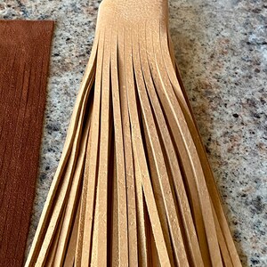 May include: A bundle of light brown leather fringe, likely for a craft project or garment embellishment.
